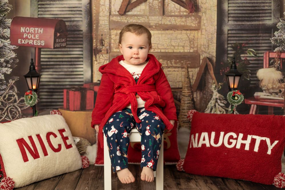 Christmas photo of little girl sitting on chair with naughty or nice pillows