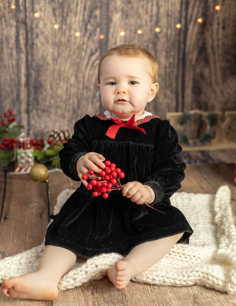 Christmas photo of baby girl in black dress with red berries