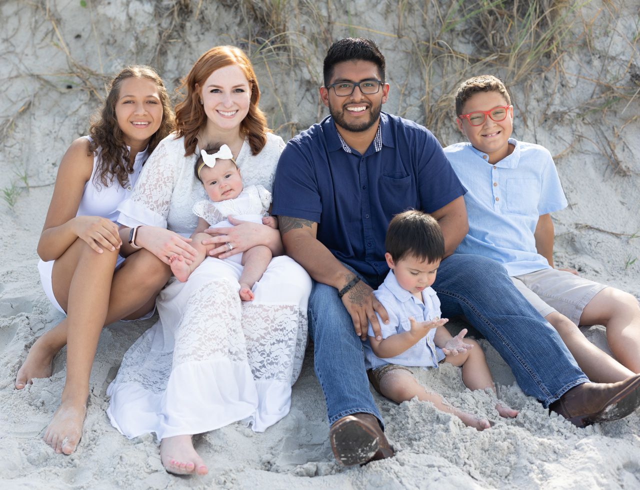 Family sitting together on rocky beach formation for casual outdoor portrait.