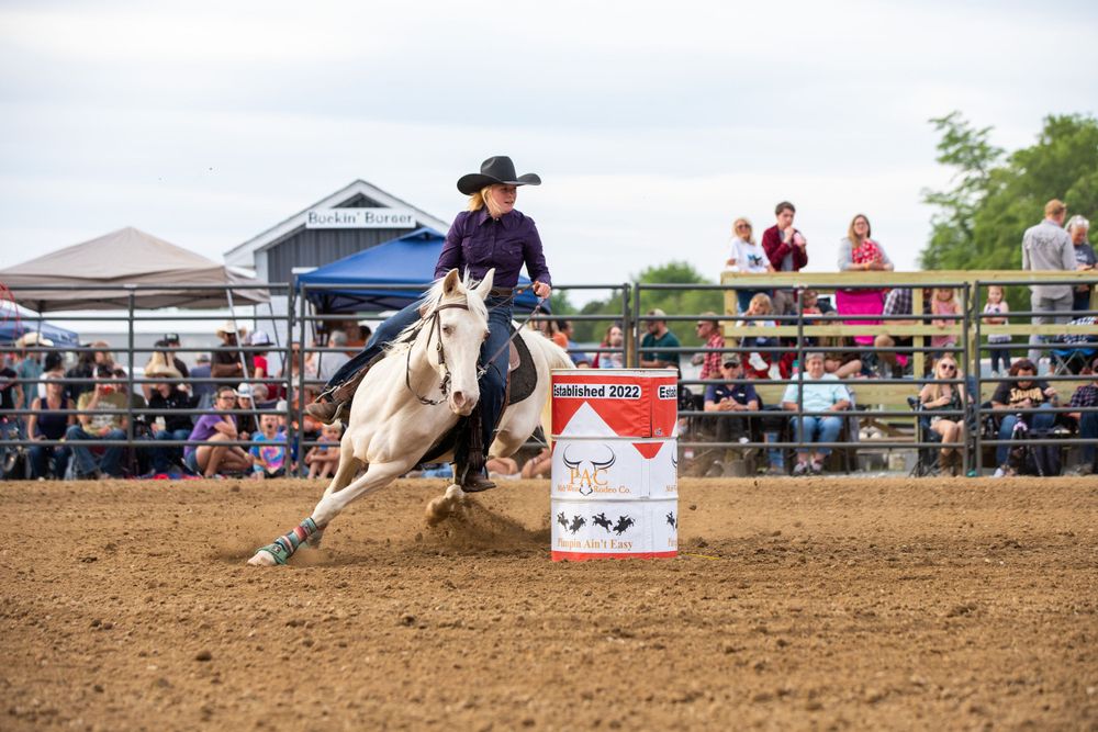 Horse and rider racing around a barrel in a rodeo arena with spectators watching.