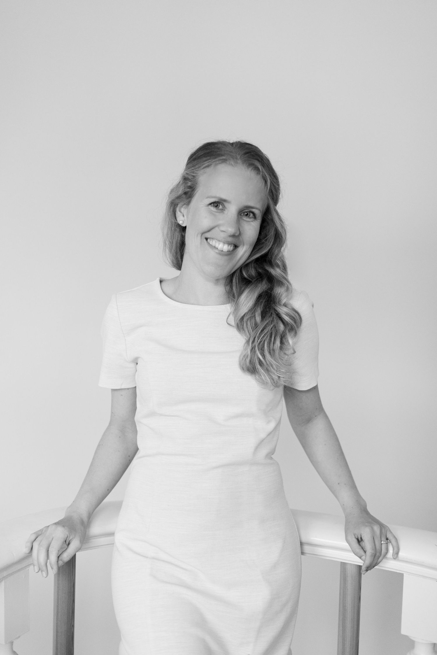 Portrait in black and white of person in white dress leaning against railing.
