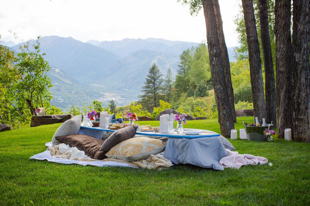 A picnic setup on a grassy hillside with scenic mountain views in the distance.