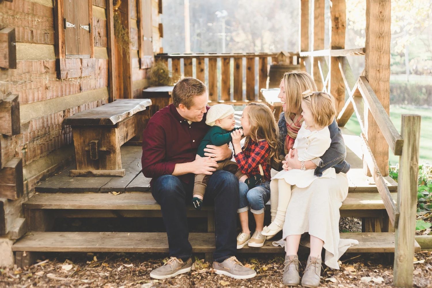 Family sharing a tender moment together on rustic wooden porch steps.