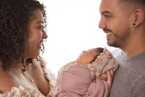 Intimate family portrait with newborn baby in pink swaddle.