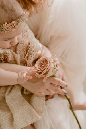 Close-up detail shot of small hands holding pink rose with gold headpiece and lace dress visible in the Hudson Valley,NY.