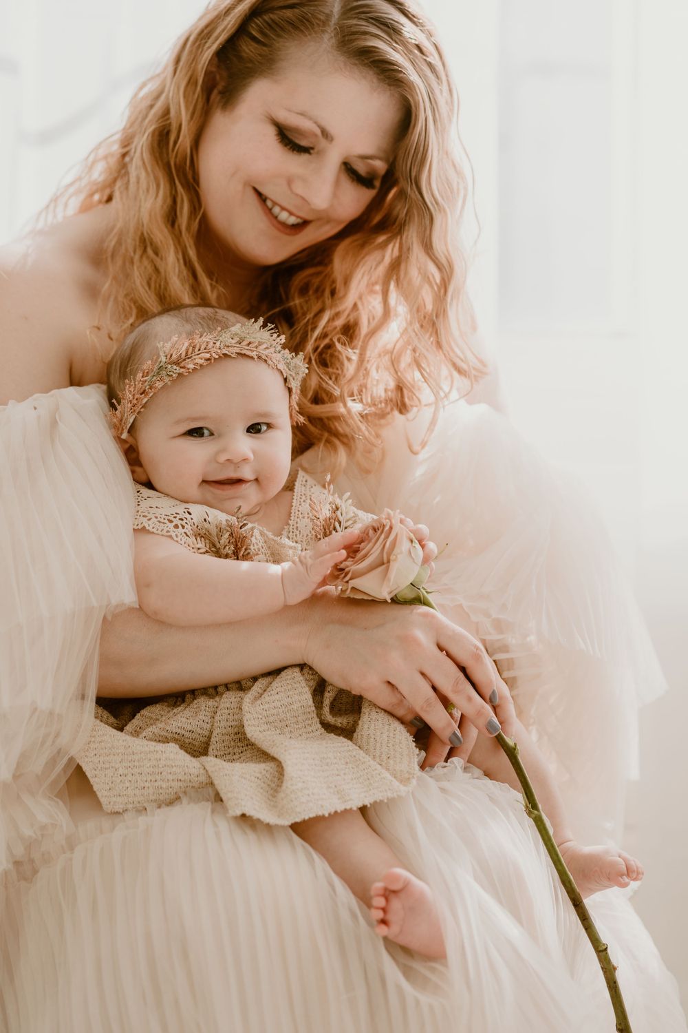 Joyful candid moment between parent and baby in matching cream outfits sharing a rose together in the Hudson Valley,NY.