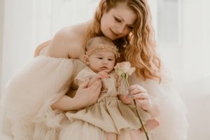 Tender monochromatic photo of parent and baby in matching cream dresses holding a single rose in the Hudson Valley,NY.