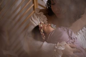 Dreamy portrait of sleeping infant in pink outfit with soft window light.