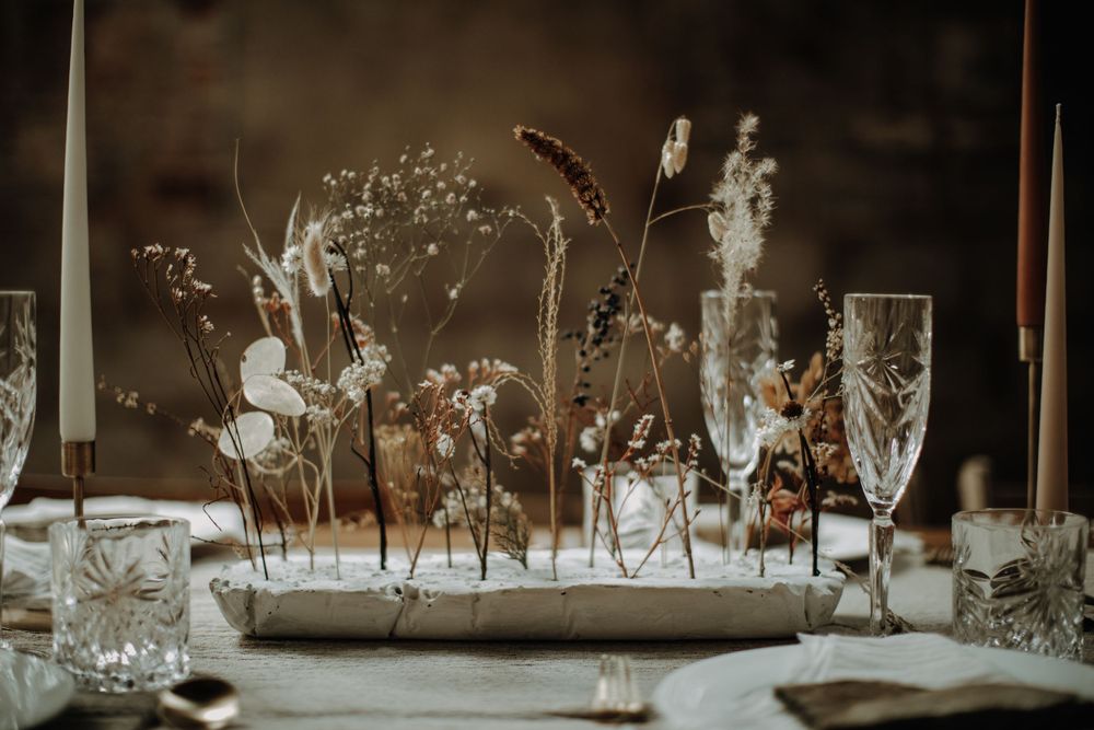 Delicate dried floral centerpiece with crystal glassware on an elegant wedding table.