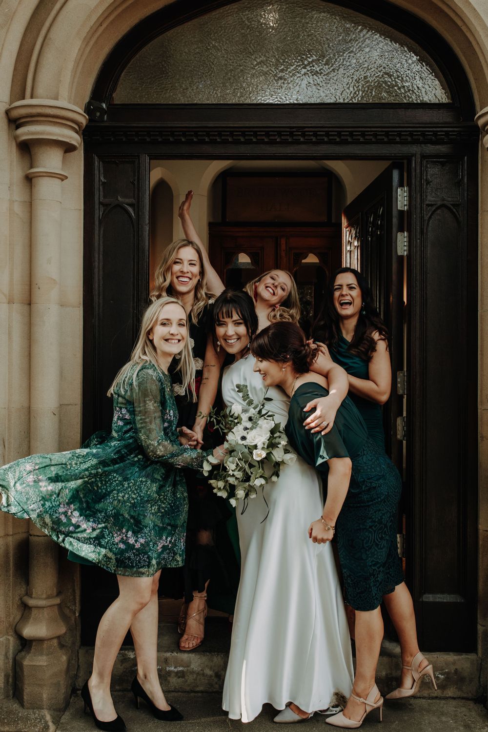 A group celebrating in formal attire shares laughter in an ornate doorway.