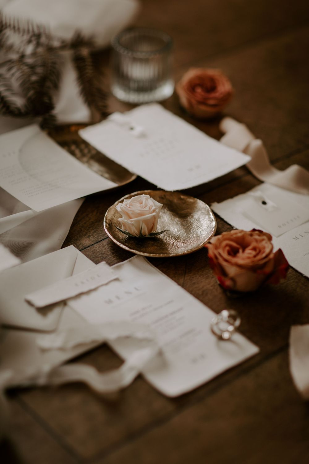 Wedding stationery and roses arranged on wooden table with romantic styling.