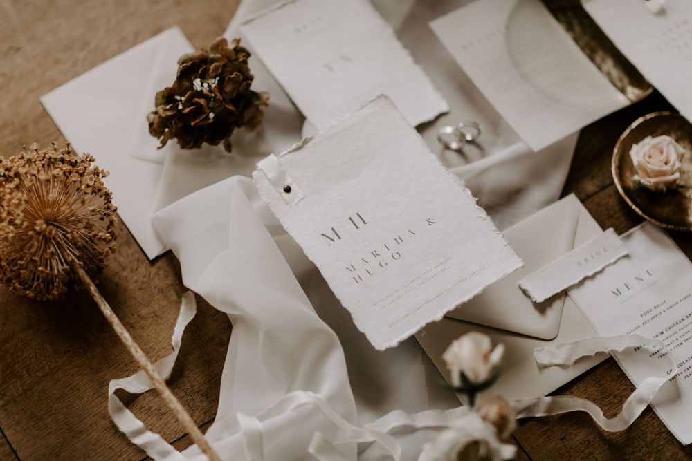 Artistically styled wedding stationery and dried flowers in neutral tones.