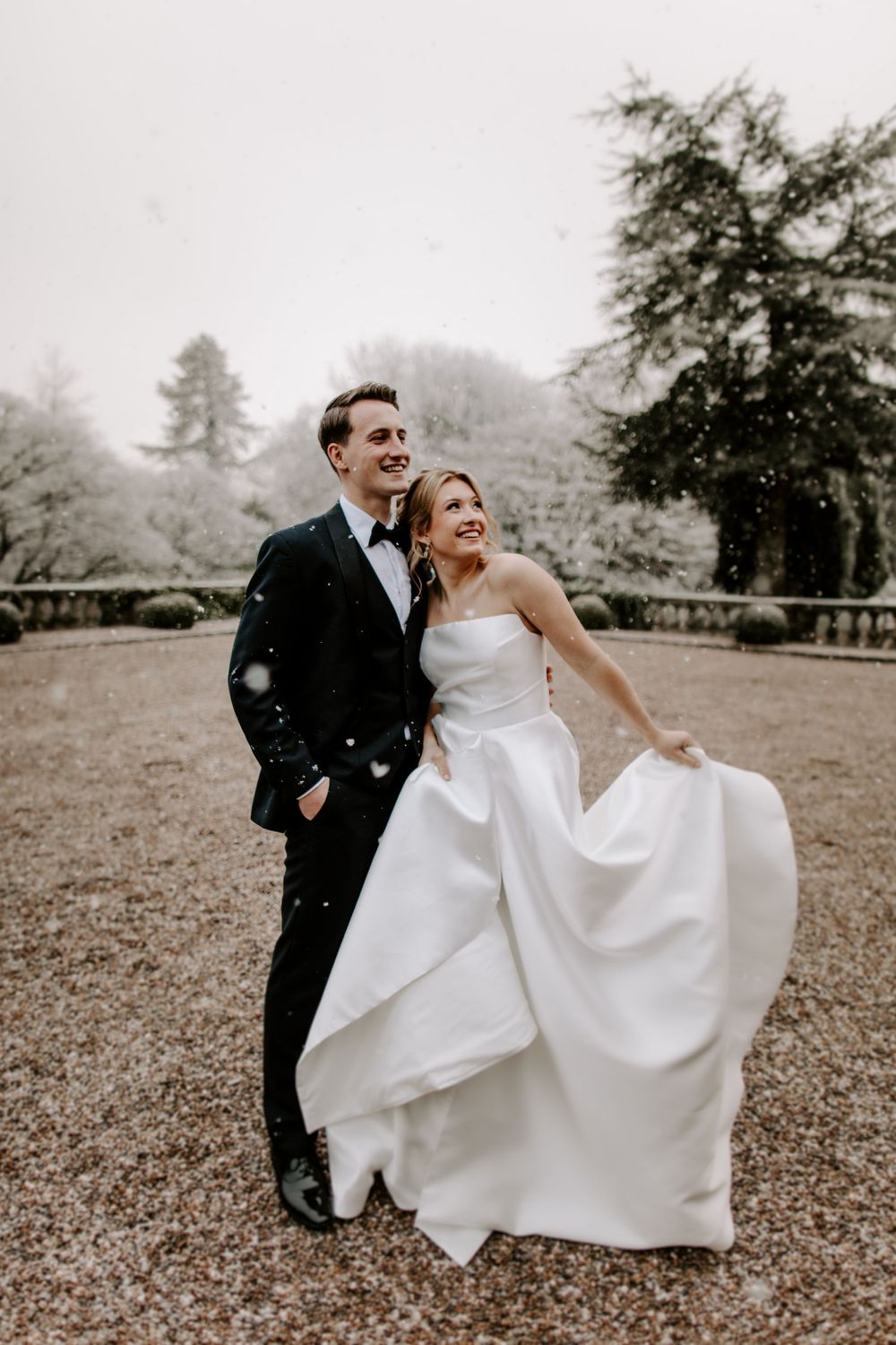 Joyful wedding couple enjoying a candid moment outdoors in formal attire.