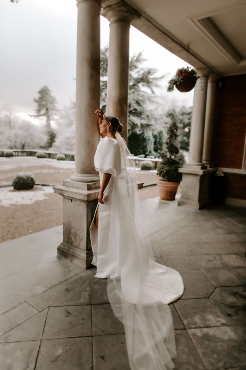 A minimalist bridal portrait on a columned porch overlooking a misty landscape.