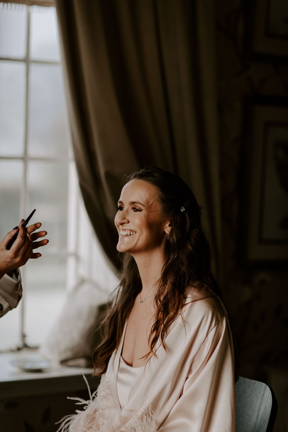 Getting ready moment with soft window light and elegant preparations.