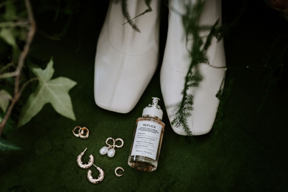 Wedding details including rings and accessories artfully arranged on green velvet.