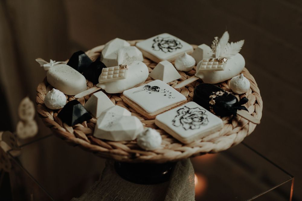 White and black decorated cookies arranged on a woven platter.