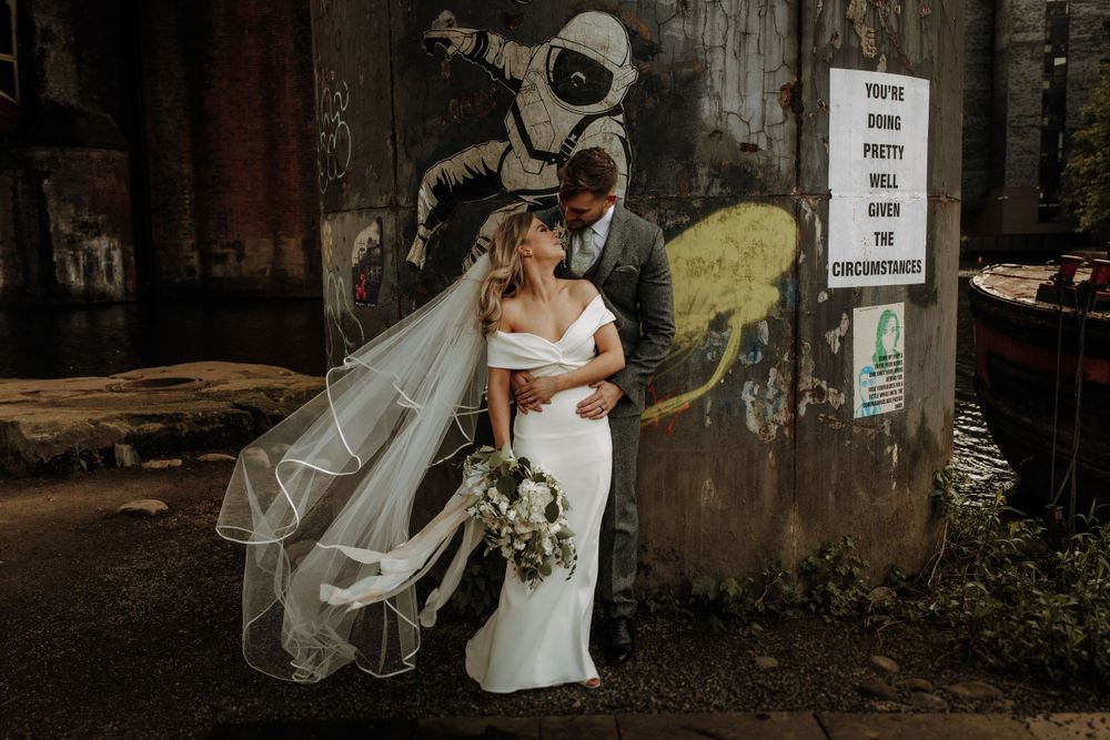 A wedding portrait against urban street art featuring a flowing veil.
