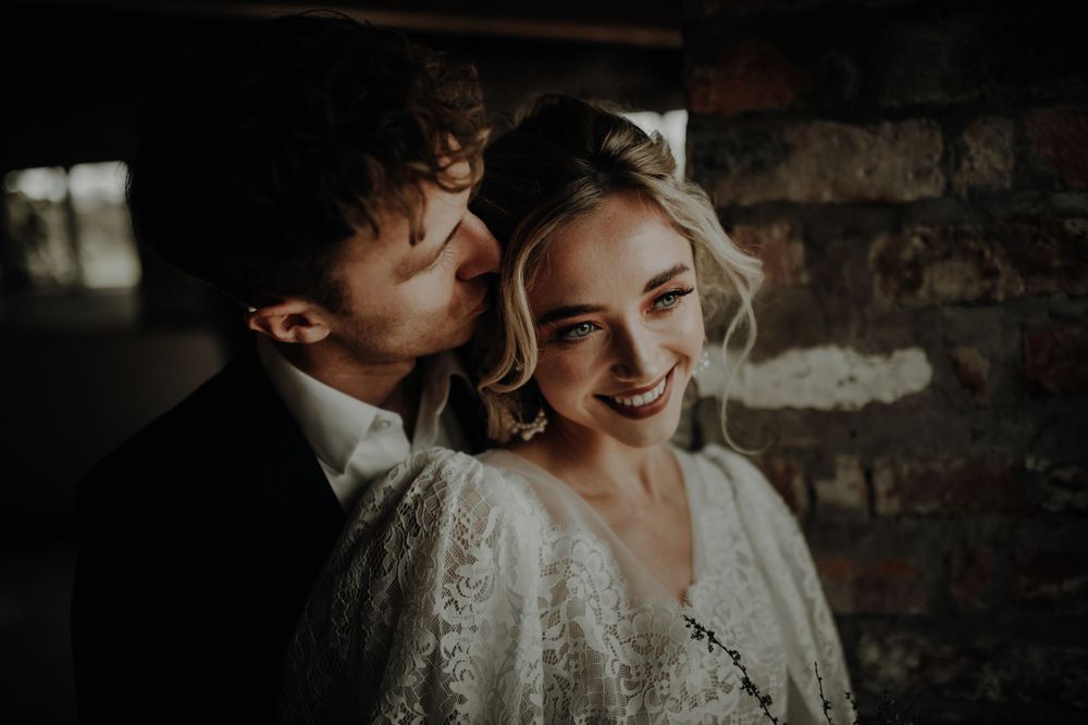 An intimate moment captured between newlyweds in a rustic brick setting.