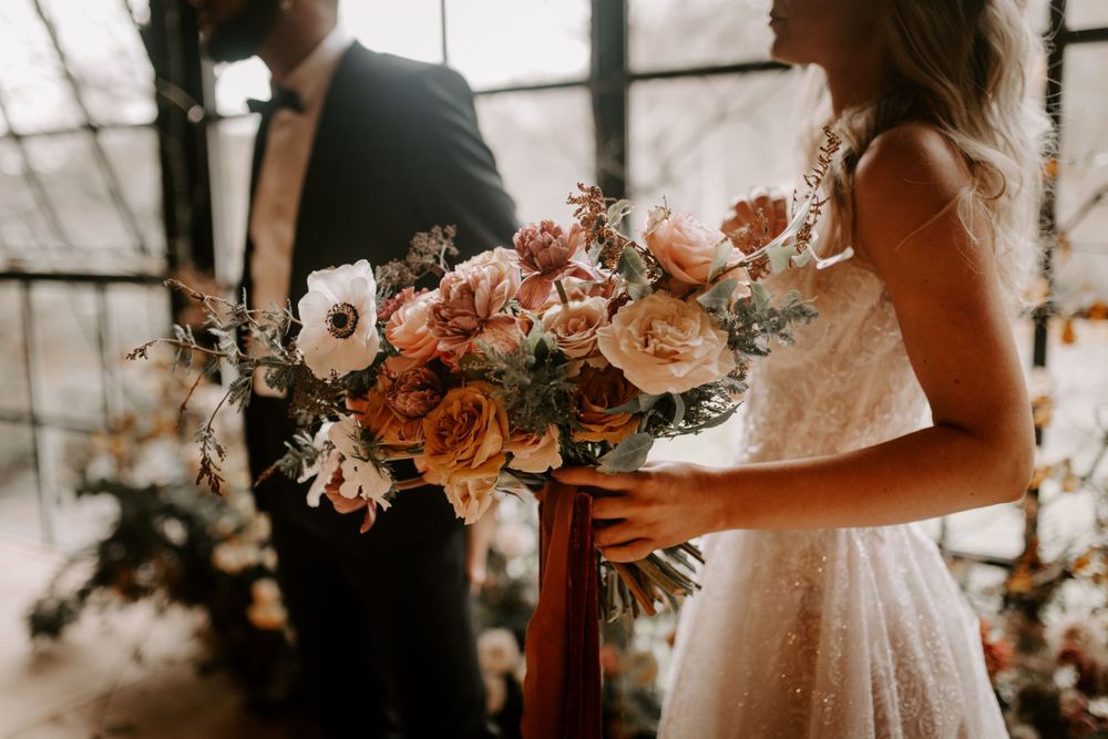 A detailed shot of a romantic peach and blush wedding bouquet with flowing ribbons.