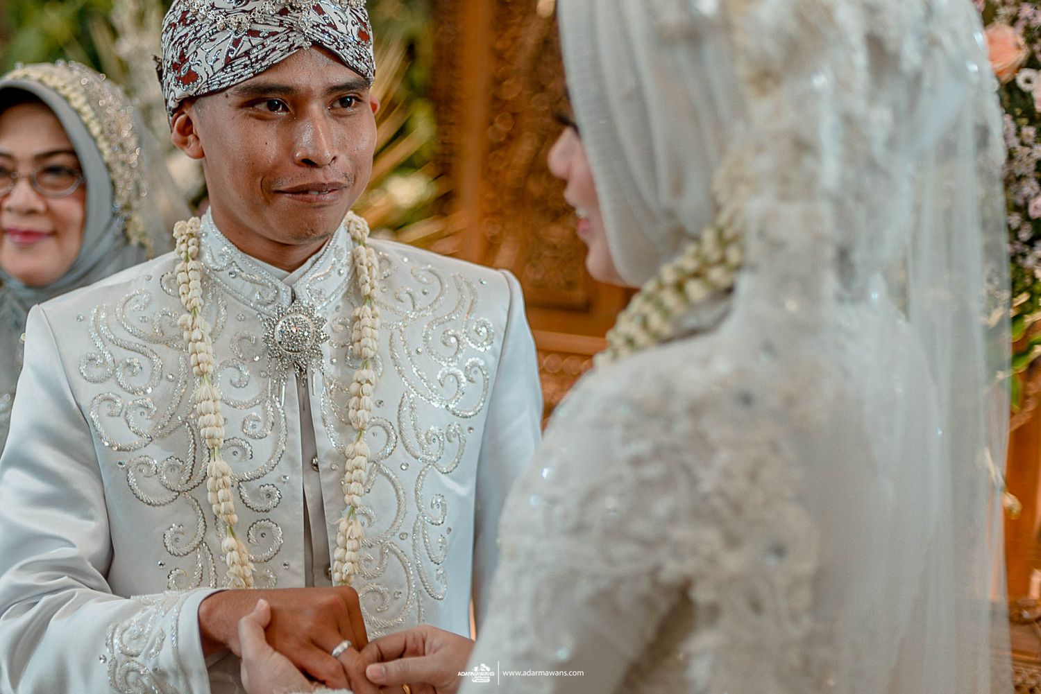 Traditional wedding ceremony with bride and groom in ornate white and gold attire.