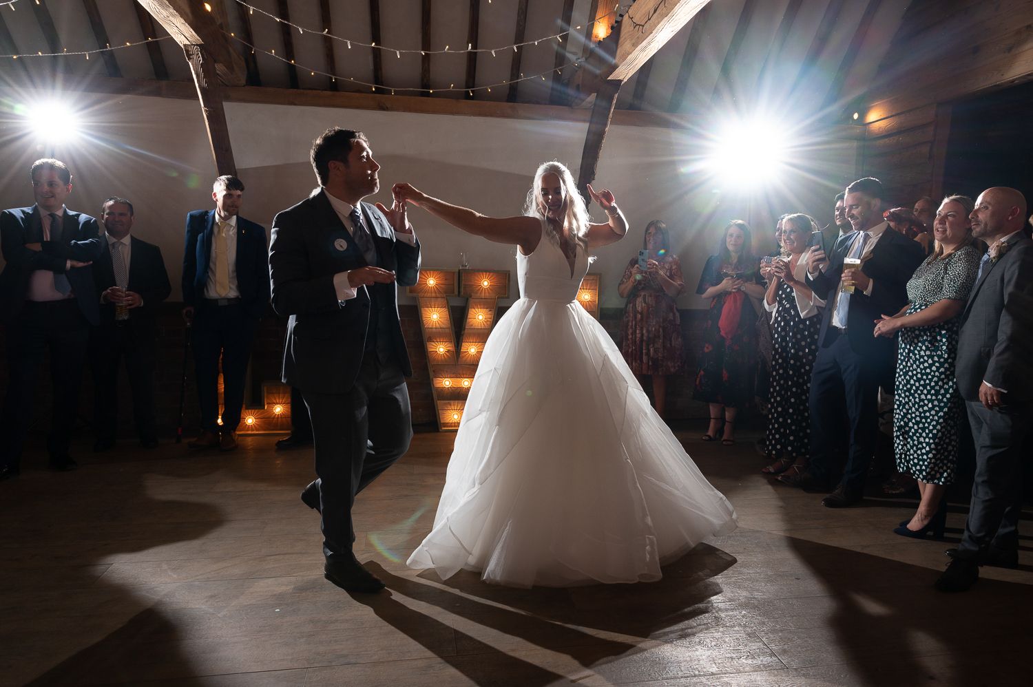 Newlyweds share their first dance under dramatic lighting at wedding reception.