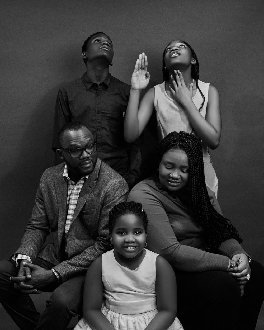 Artistic black and white portrait of family group posing together against neutral background.