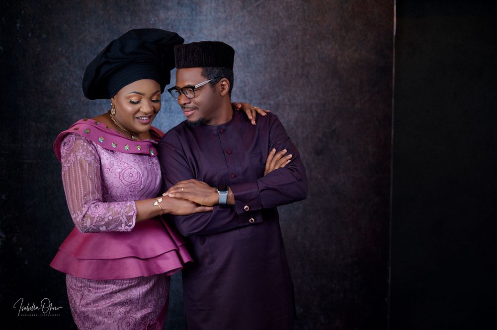 Couple in coordinated purple formal wear pose intimately during studio portrait session.