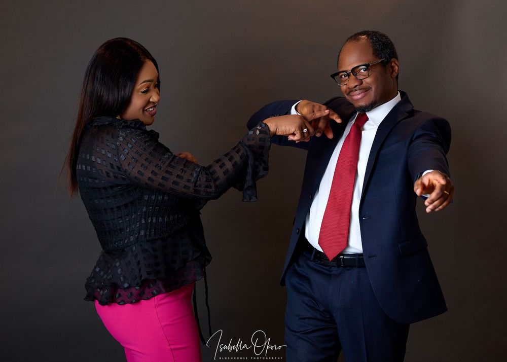 Playful professional studio portrait of two people in business attire doing fist bump.