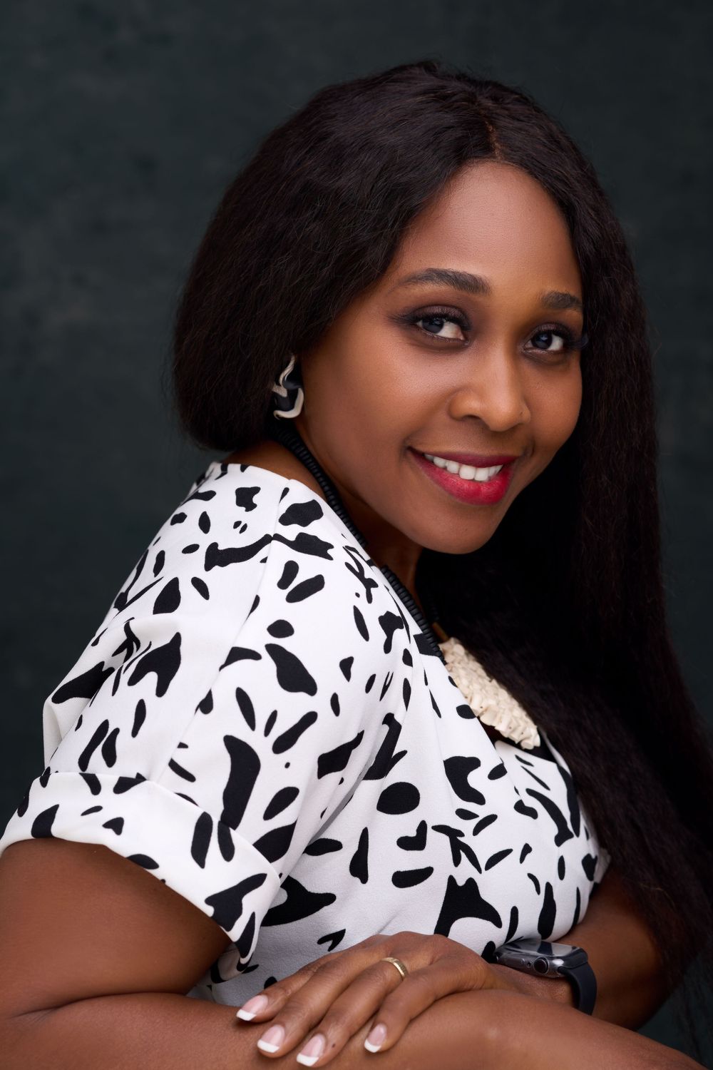 Close-up portrait of woman in black and white patterned blouse against dark backdrop.
