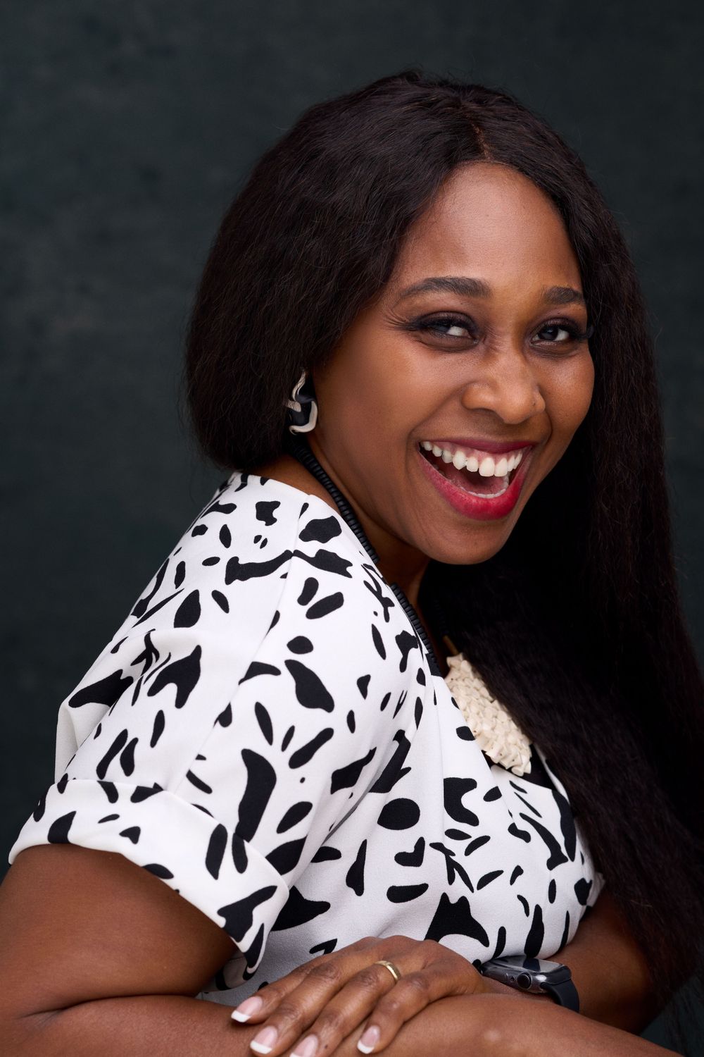 Woman laughing in black and white patterned top during studio photoshoot.