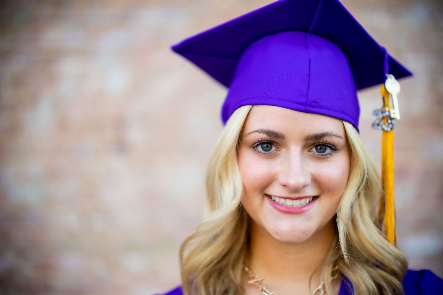 Graduate wearing purple cap and gold tassel during graduation ceremony.