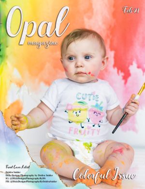Adorable baby on Opal Magazine Feb cover, covered in paint, wearing Cutie Fruity shirt, holding paintbrush.