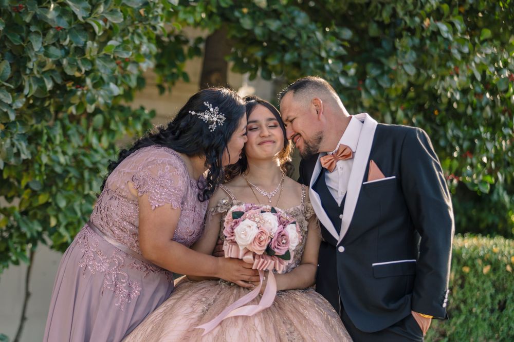 Intimate family moment captured outdoors with pink gowns and formal attire.