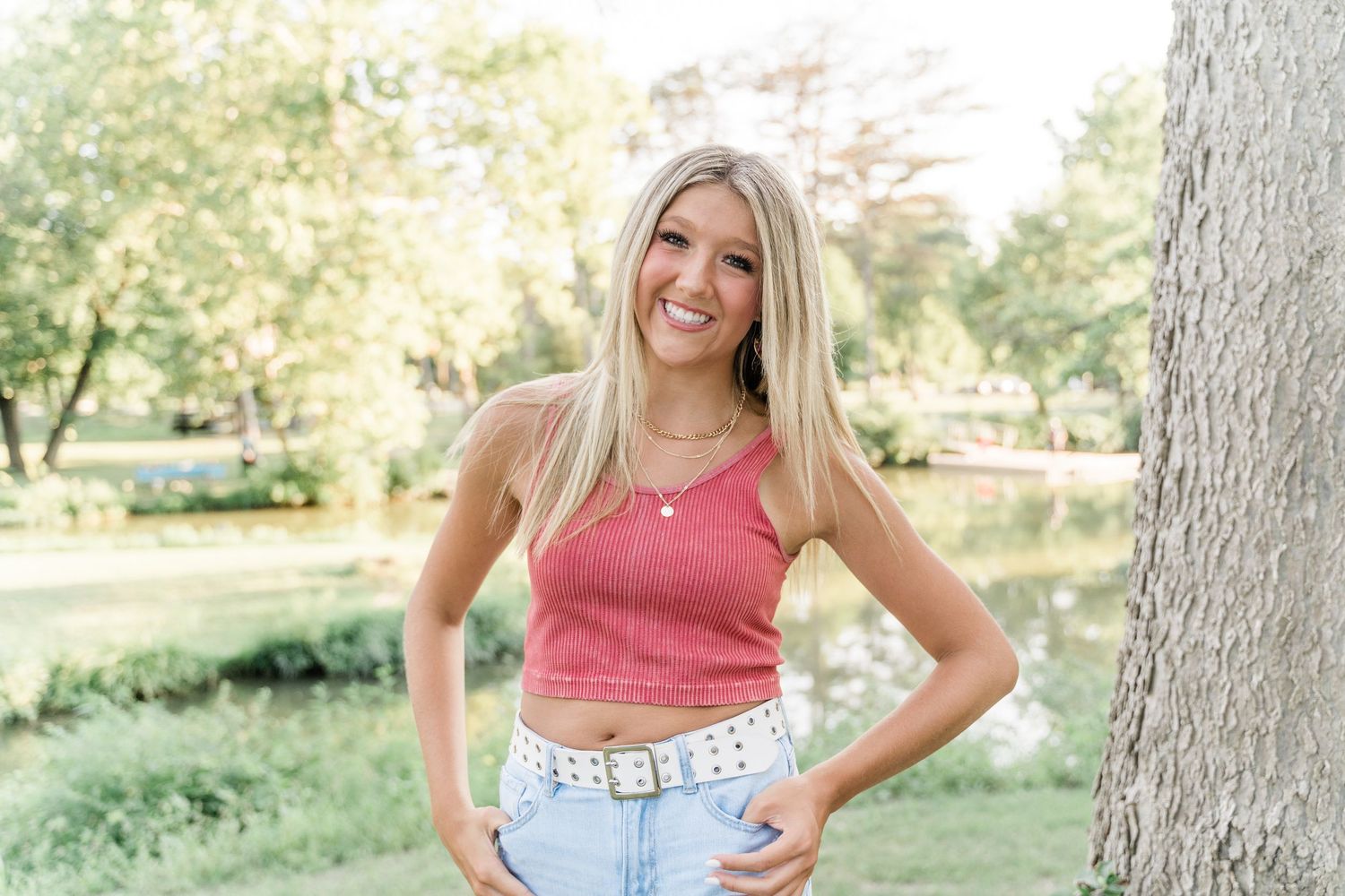 Senior portrait of girl in light denim and blush top leaning on bridge railing at Side Cut Metropark.