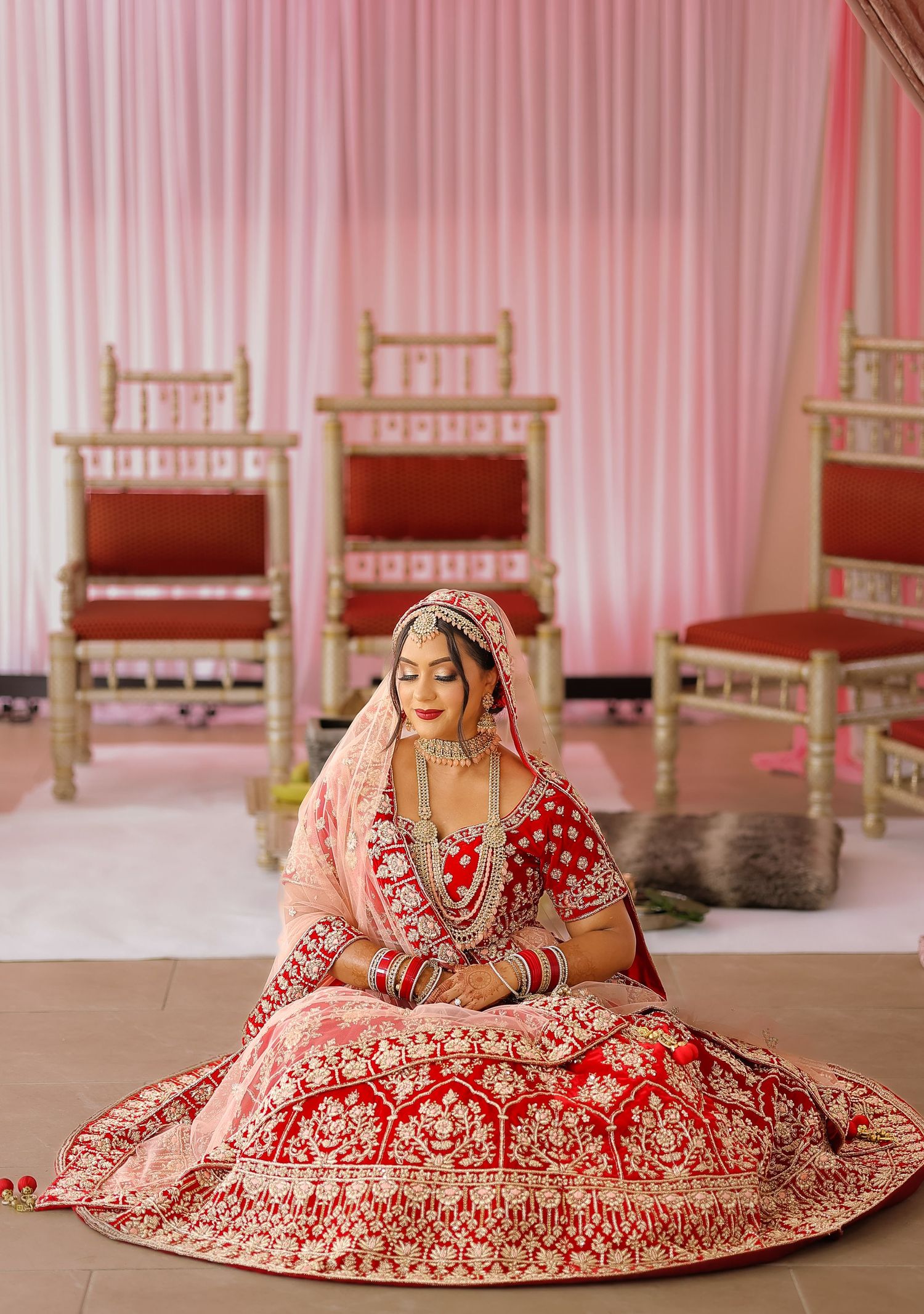 Newly wed Bride laying on floor wearing a red patterend lehenga awaiting her Mehendi