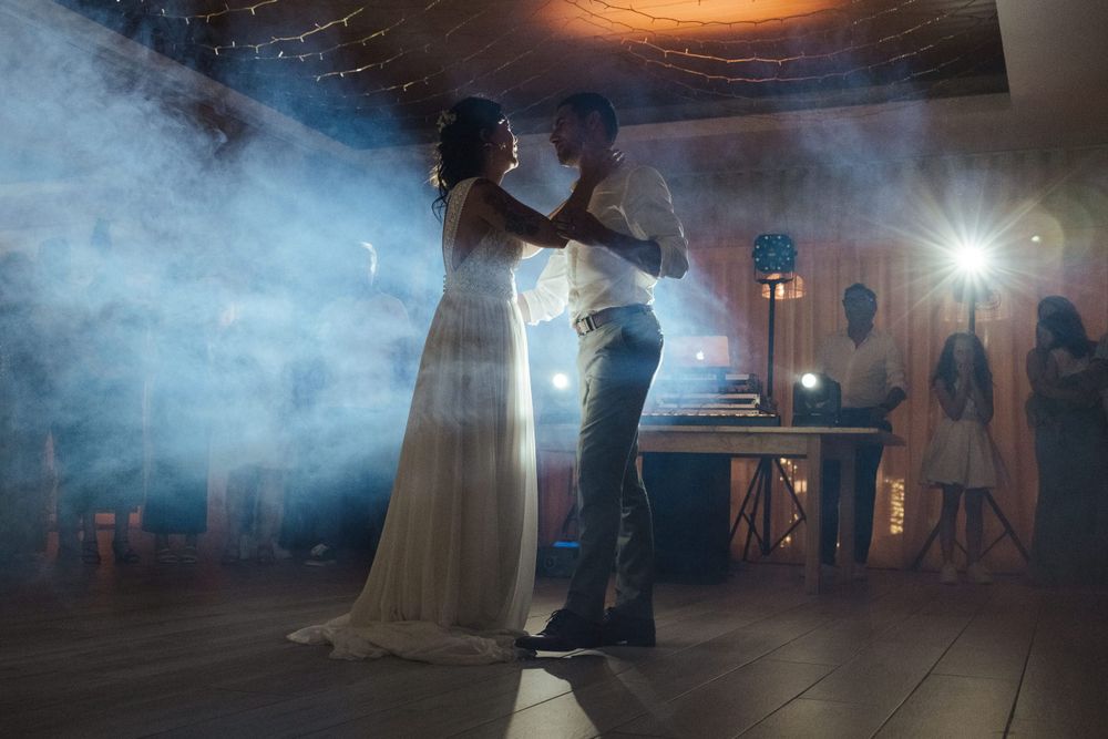 Ambiente de pista de dança de festa de casamento com atmosfera envolvente, nevoeiro e iluminação dramática numa receção noturna.