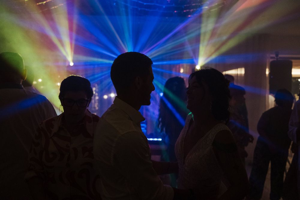 Espetáculo de luzes ao estilo de um concerto, com feixes de laser azuis e efeitos coloridos, criando uma atmosfera dramática.