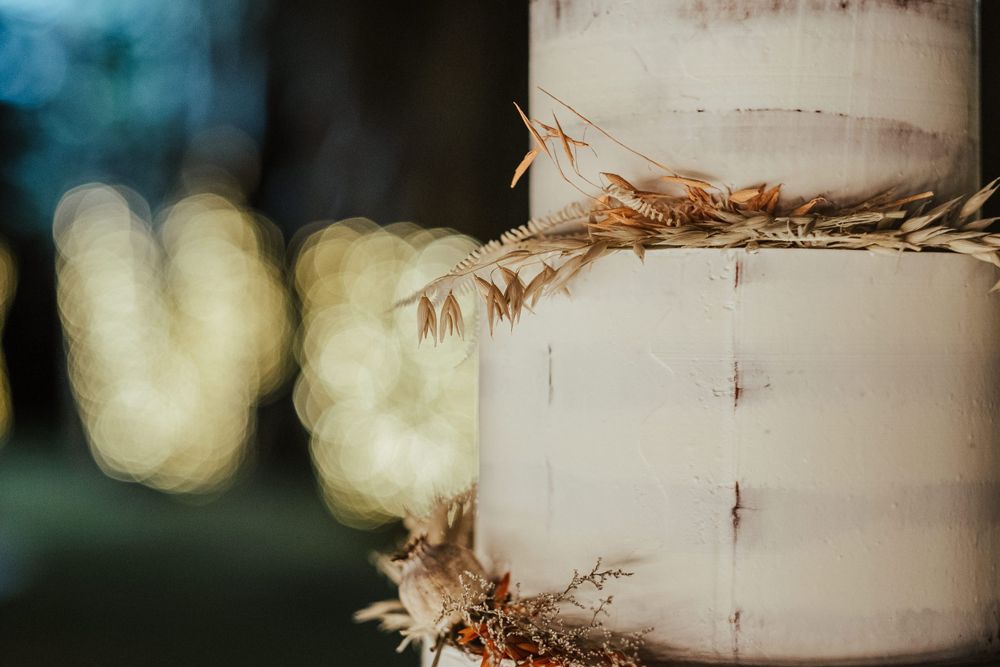 Elegante bolo de casamento branco de vários andares com decoração rústica de flores secas.