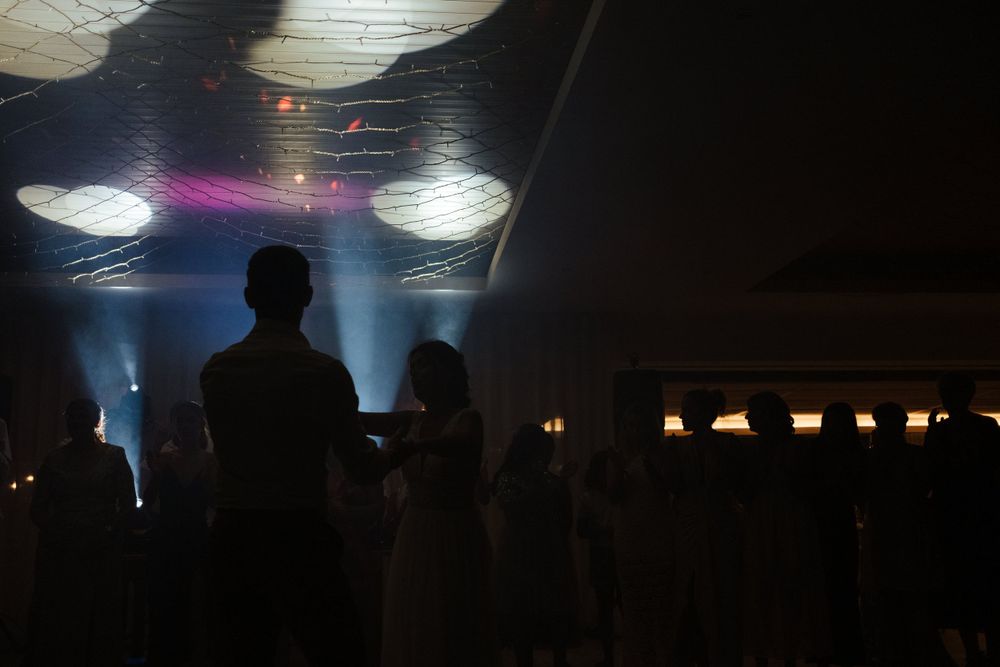 Silhuetas numa discoteca escura com iluminação dramática vinda de cima e efeitos de fumo.