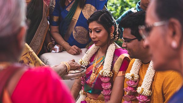 Wedding ceremony showing traditional Indian rituals with attendees in vibrant saris and garlands.