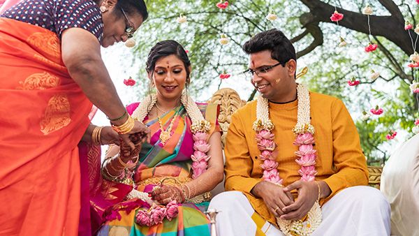 Wedding ceremony participants performing traditional rituals with pink and yellow decorations.
