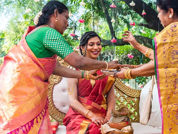 Traditional Indian pre-wedding ritual taking place outdoors with women in colorful saris.