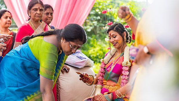 Ceremonial ritual being performed under pink decorated outdoor canopy.