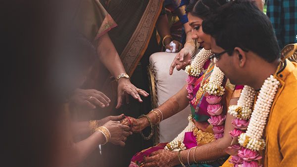 Traditional Indian wedding ceremony showing hands exchanging ritual items.