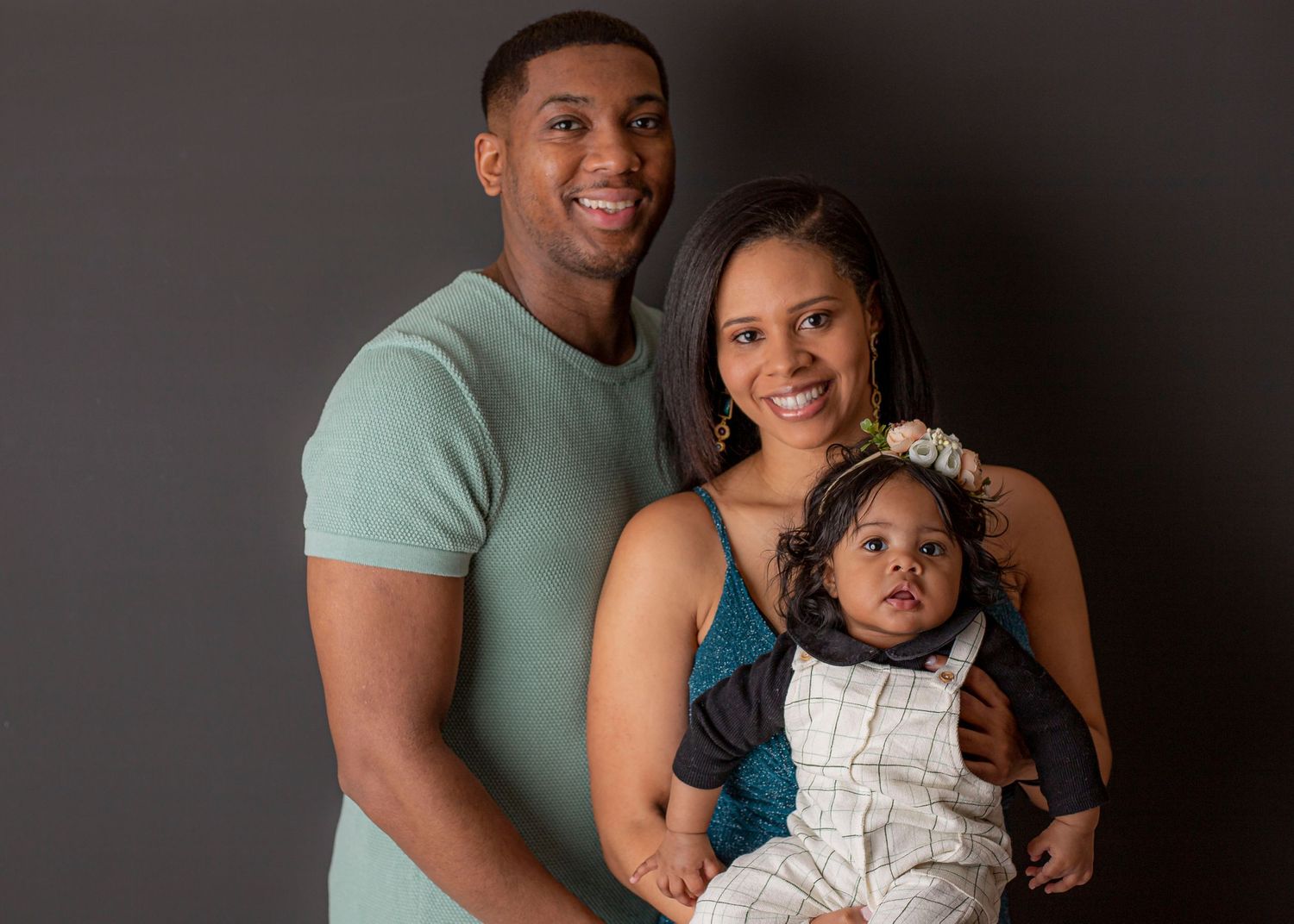 Family portrait against dark background with parents in casual attire.