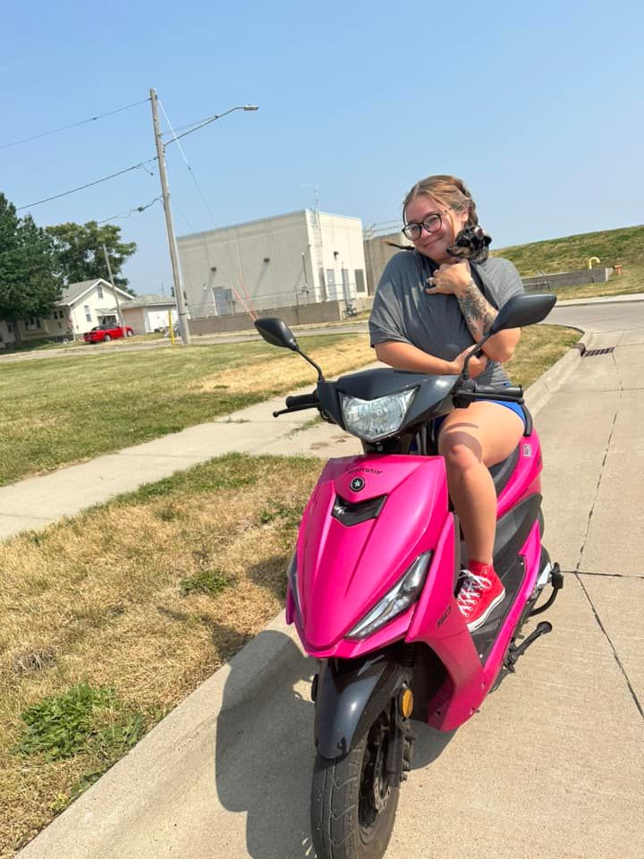Person riding a bright pink motorcycle on an empty suburban street.