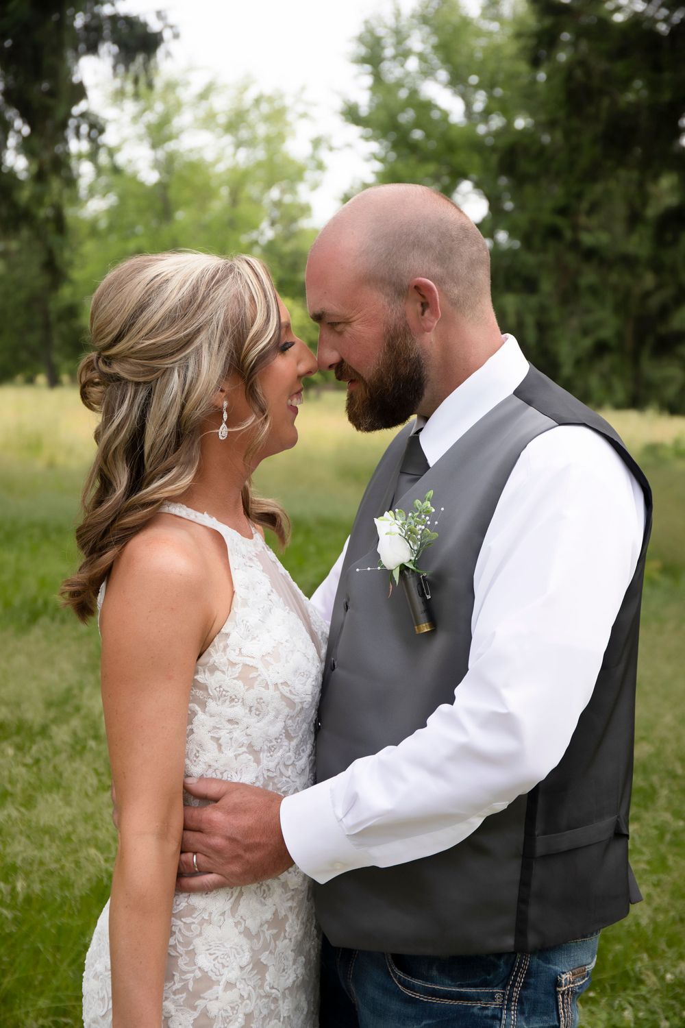 Wedding couple shares intimate moment in outdoor setting with lush greenery background.