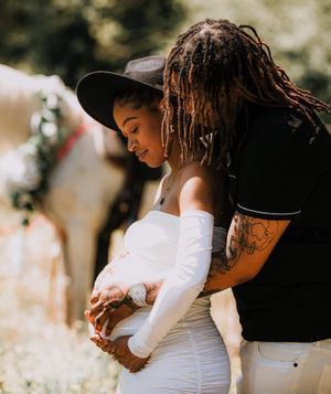 A tender moment between two people standing together in sunlit outdoor setting.