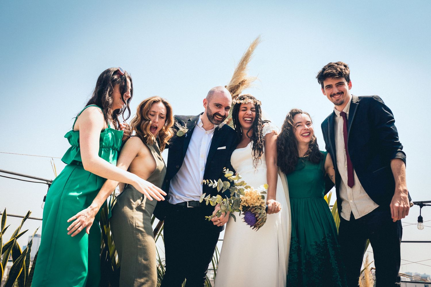 Wedding party members share candid laughs and hugs during outdoor celebration.